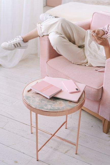 Person relaxing on pink sofa with notebook and smartphone, perfect for lifestyle themes.