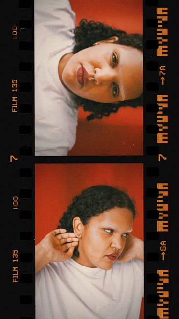Artistic vertical photobooth portrait of a woman with curly hair against a vivid red background.