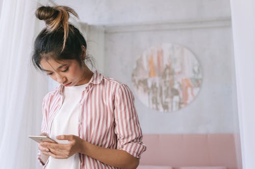 Photo of a Woman in a Striped Shirt Using Her Cell Phone