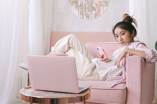 Free Woman Sitting on Sofa Chair Holding a Smartphone Stock Photo