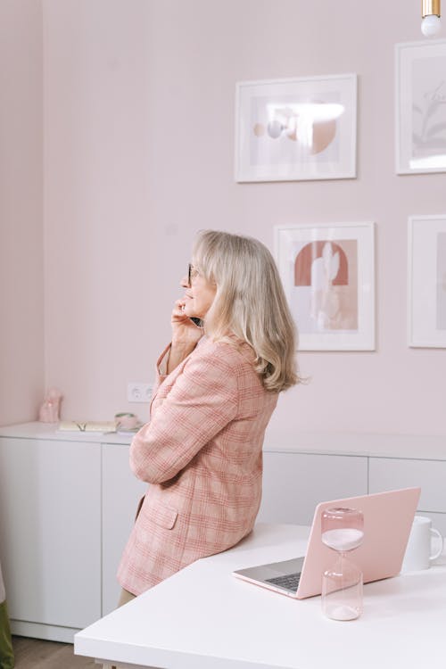 Free Woman in Pink Plaid Blazer Leaning on White Table Stock Photo