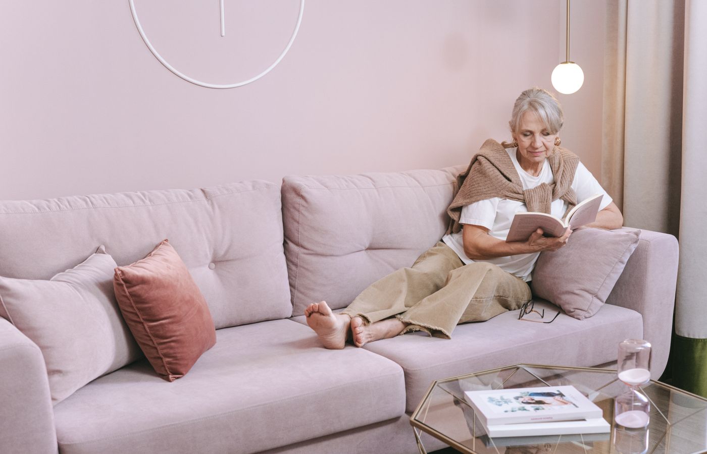 An older woman reading quietly on a sofa in the evening.