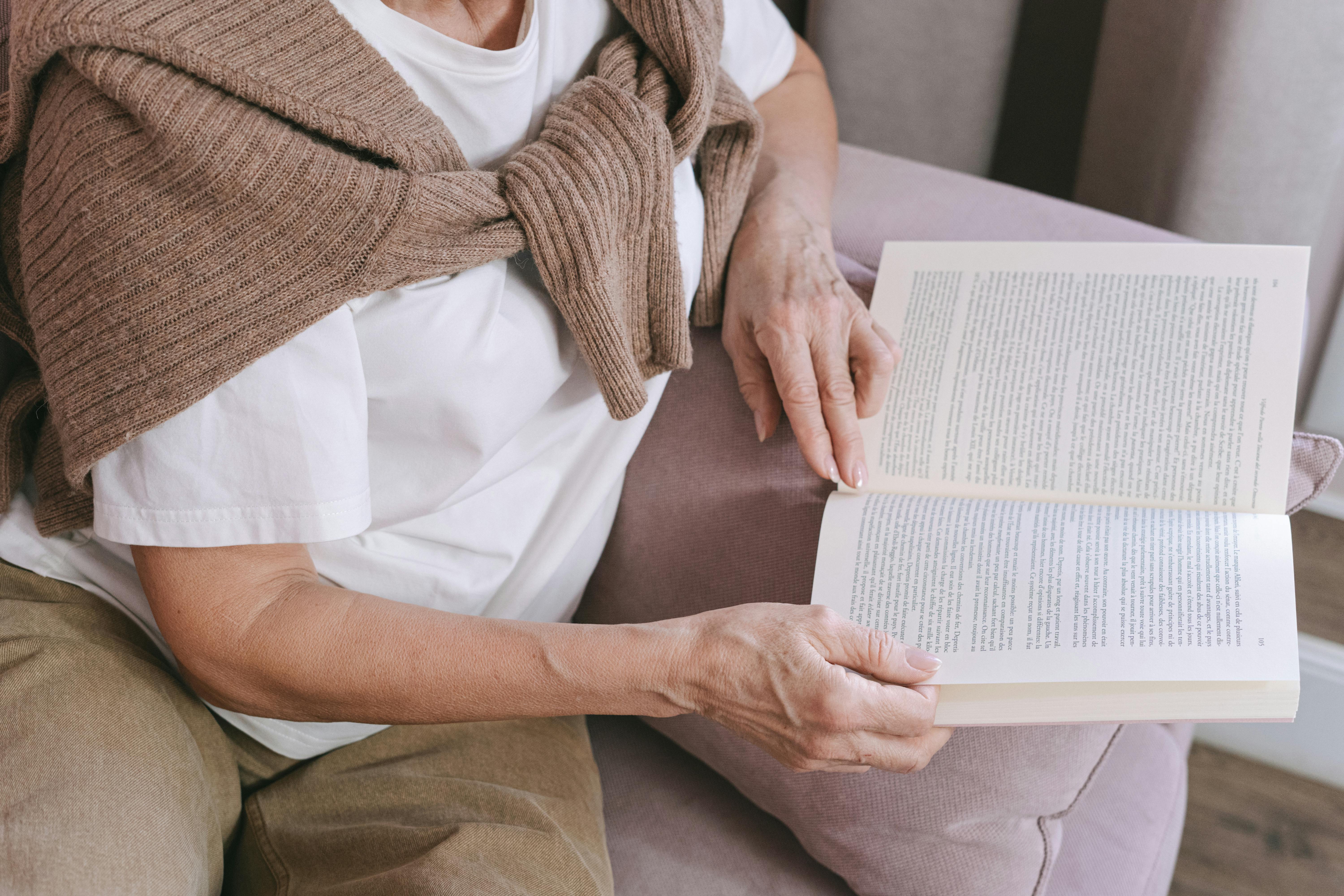 Adult woman reading on a sofa in casual attire, enjoying leisure time.