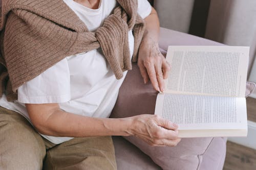 Free Person in White Shirt and Brown Sweater Reading Book Stock Photo