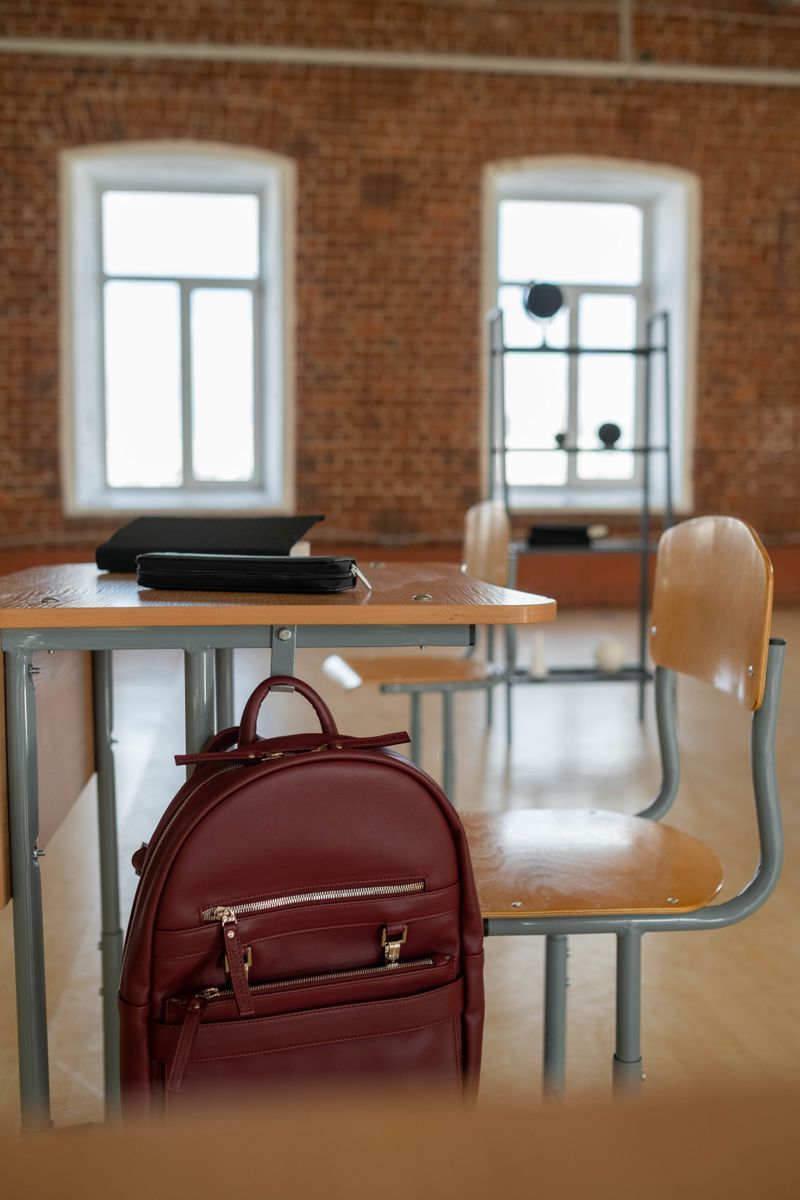 A backpack hanging on a wooden desk in a bright classroom