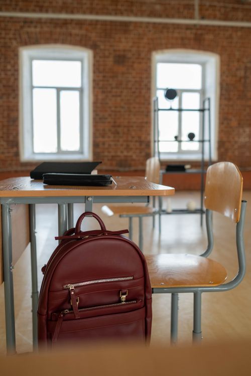 Free Spacious classroom setting with a backpack on a desk and chairs. Stock Photo