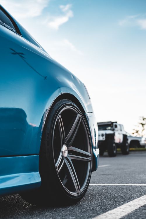 Free Close-up of a blue car with stylish rims parked on an urban road under a clear sky. Stock Photo