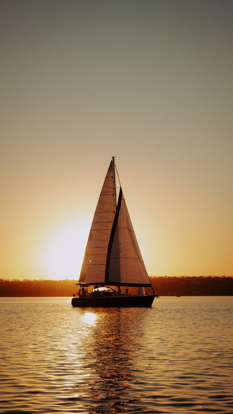 Yacht Sailing On River At Sunset