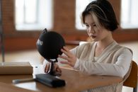 Woman in White Sweater Holding Black Round Ball