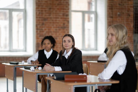 Students in uniform sitting at desks in a bright, brick-walled classroom.
