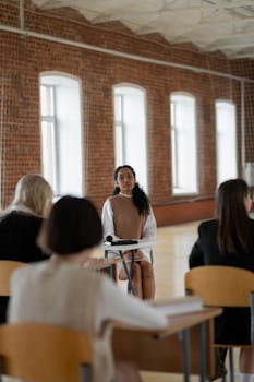 Young adult students in a college classroom engaging in a discussion with a lecturer.