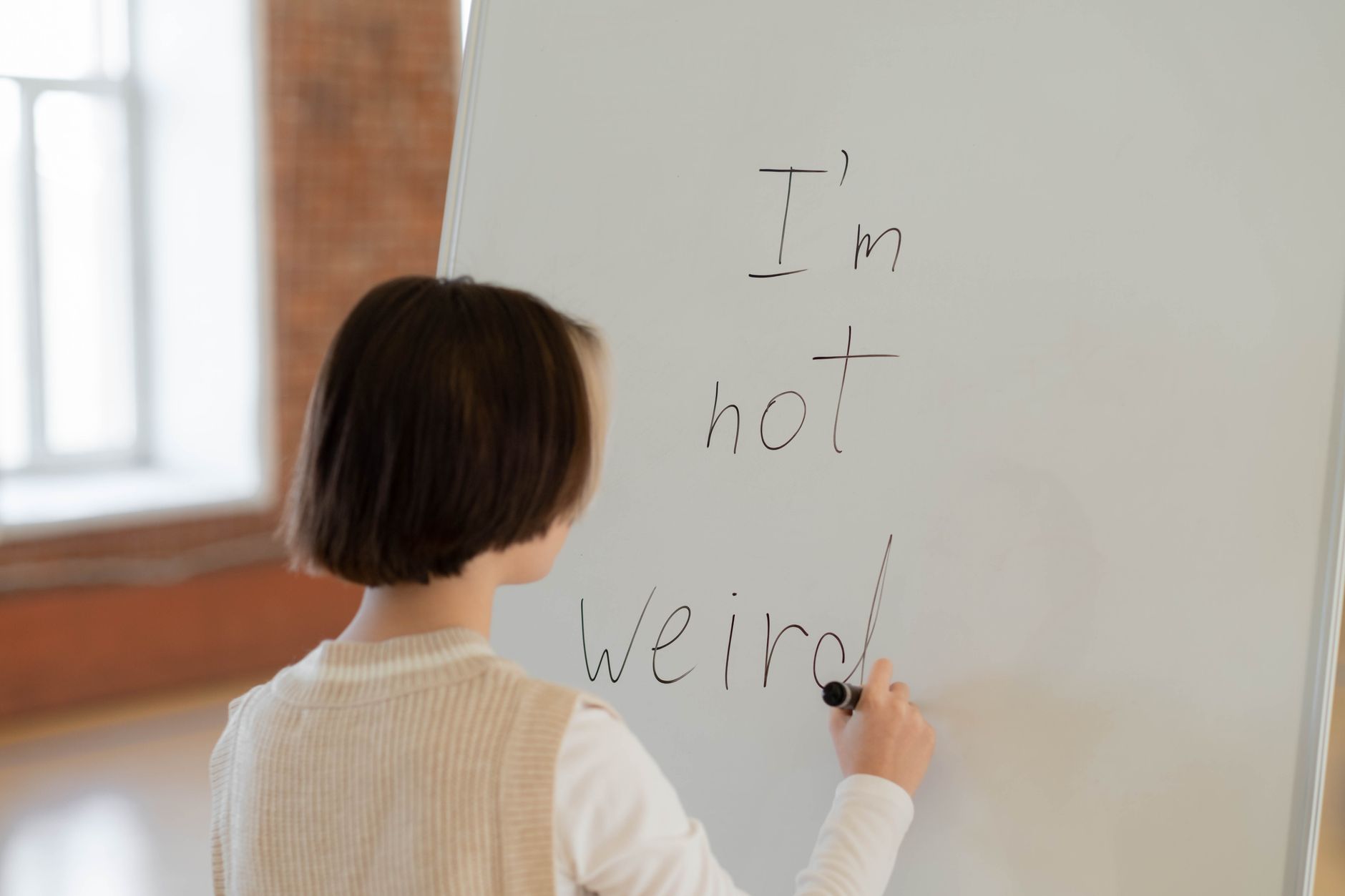 A person at a whiteboard writing short phrases in a small bright room, working through positioning options