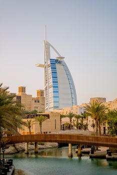 Iconic Burj Al Arab surrounded by Dubai's urban skyline at day.