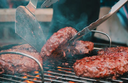 Close-up of juicy burgers being expertly cooked on a smoky barbecue grill.