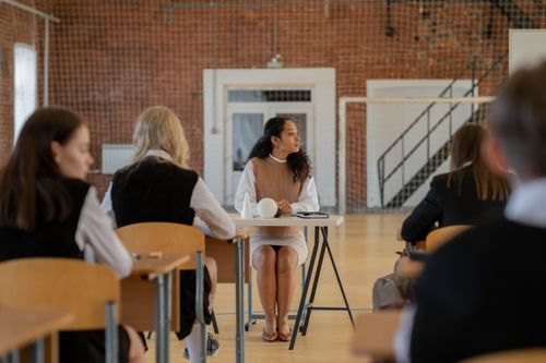 Free Teacher sitting at desk during class in a school gymnasium. Stock Photo