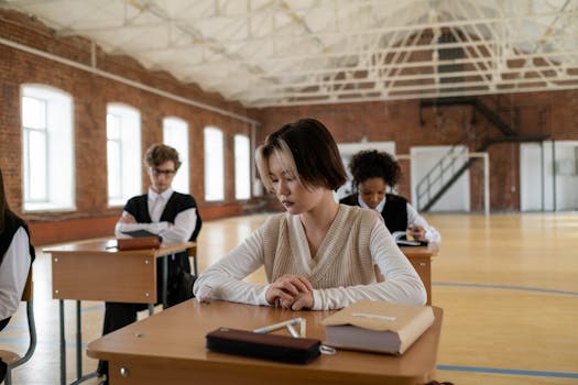 Students in uniforms studying in a spacious vintage school hall with natural light.