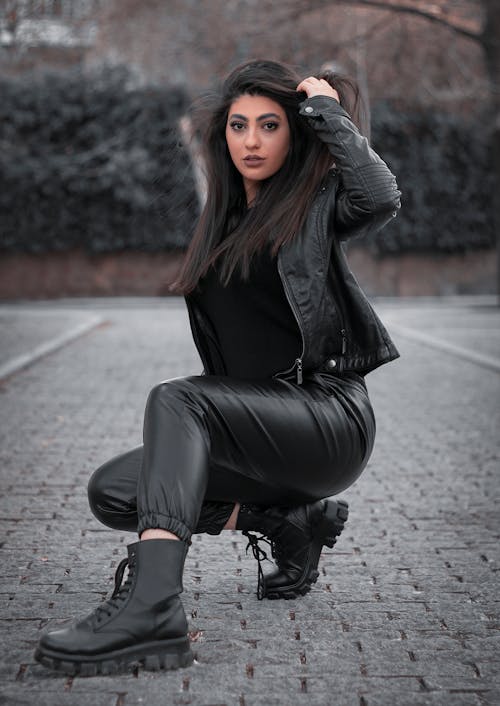 Woman in Black Jacket  Kneeling on the Stone Pavement