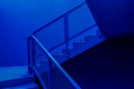 Staircase with metal railing in contemporary building designed in minimal style and illuminated by blue neon light