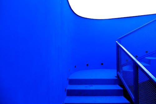 Stairway with metal railings inside contemporary building in minimal style with blue neon illumination