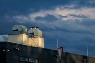 Low angle of metal pipes of ventilation system located on rooftop of industrial building against cloudy sky
