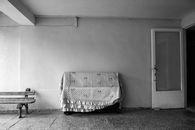Black and white piano covered with plaid placed in hall of shabby building