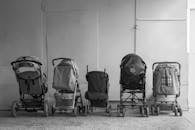 Old baby carriages placed in row near wall in hallway of aged residential building