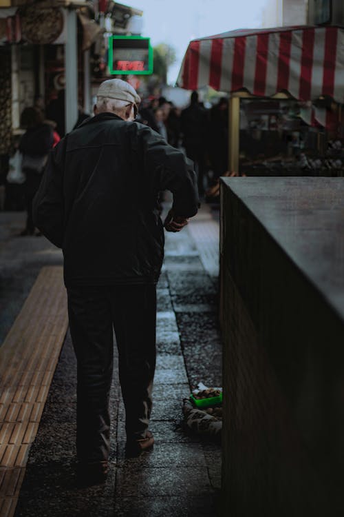 A Man in Black Jacket Walking on the Street