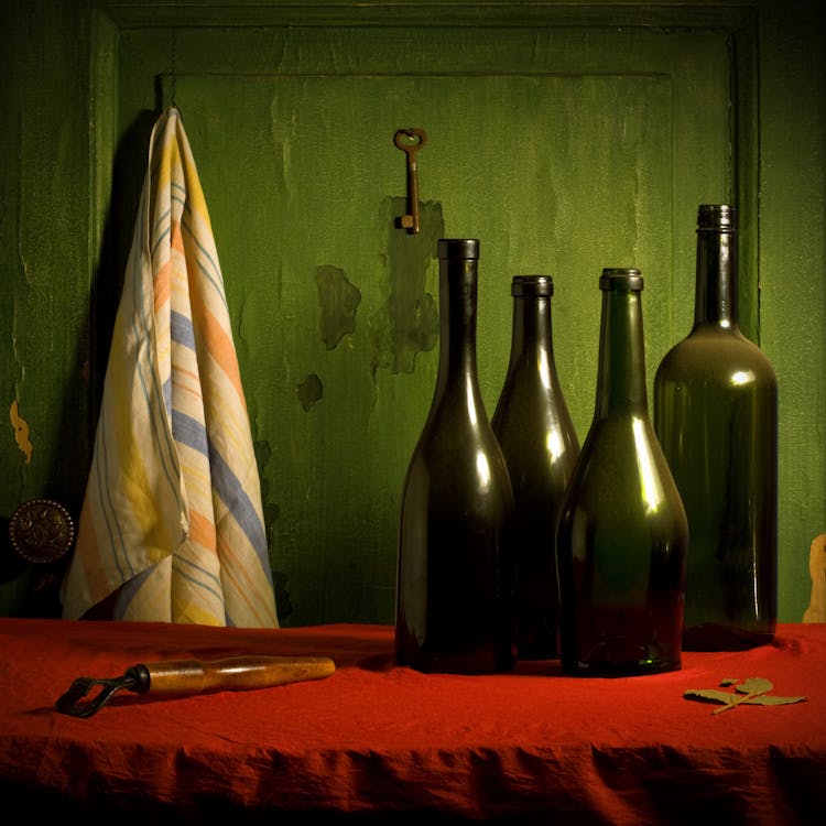 Free Green glass bottles placed on table against wall with towel in rustic kitchen Stock Photo