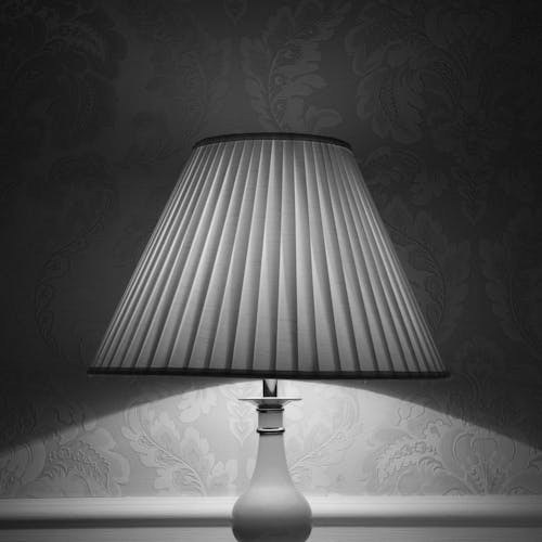 Black and white glowing lamp placed near wall and illuminating room designed in retro style