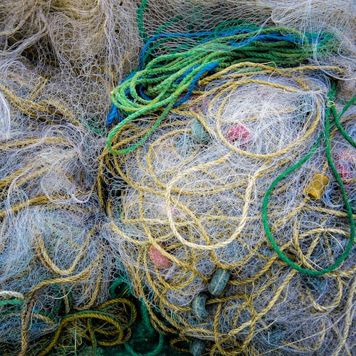 Top view of full frame background of pile assorted fishing nets and colorful ropes