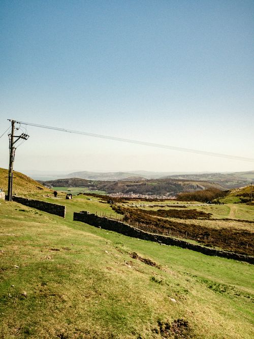 Free Picturesque scenery of utility line in verdant grassy hilly terrain under blue sky Stock Photo
