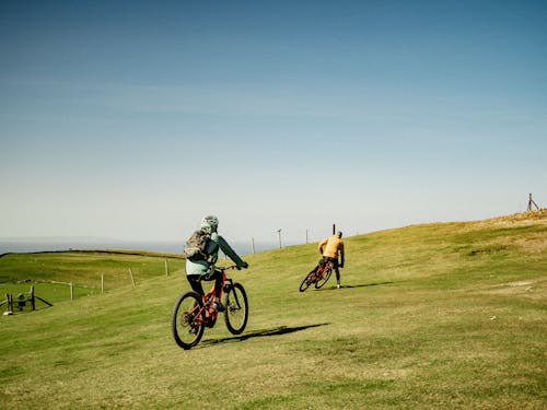 Two Bikers Riding a Bike on a Grassy Field