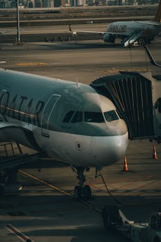 Aircraft docked at airport gate with passenger jet bridge during daytime.