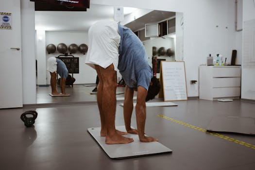 A man stretching on a gym mat with reflections in the mirror, promoting fitness health.