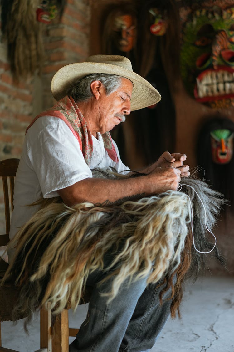 Elderly Man In White Shirt Weaving A Wig