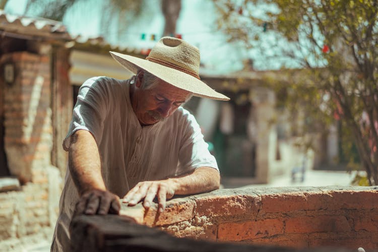 An Elderly Man Standing Beside A Brick Pit