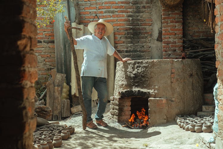 A Man In Pottery Business Using A Brick Pit Oven