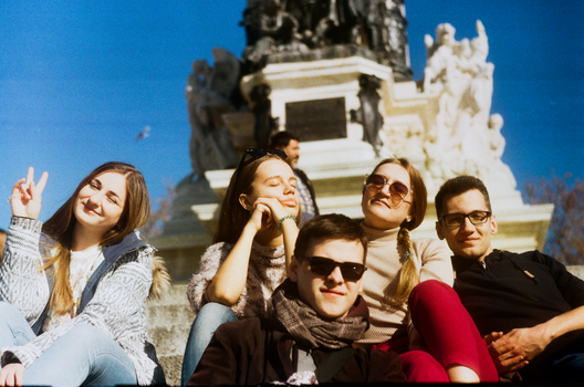 Group of smiling young adults enjoying a sunny day at a monument outdoors.