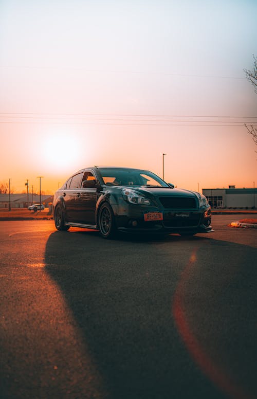 A Black Sedan Car Parked on the Road during Sunset