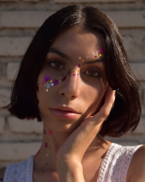Free Artistic close-up portrait of a woman with glitter stars on her face outdoors. Stock Photo