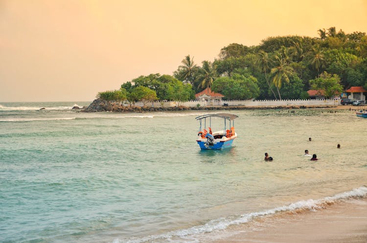 Photograph Of People Swimming Near A Boat