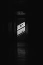 Black and white of empty neglected apartment with doorway and dim light with shadow on wall with power adapter and socket