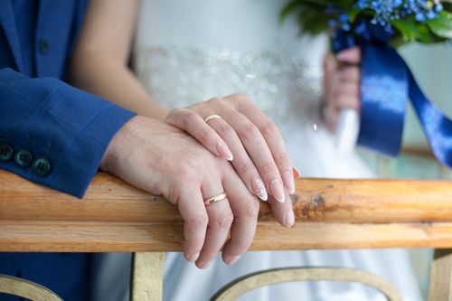 Free A close-up of a married couple gently holding hands, showcasing wedding rings and love. Stock Photo