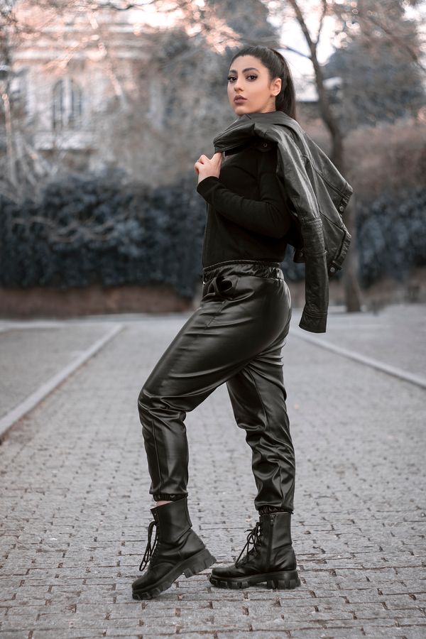 Woman in leather jacket with black bodysuit and tailored trousers