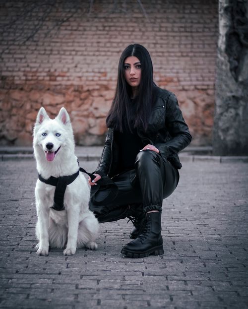 Free Fashionable woman kneeling with her Siberian Husky on a stone pavement. Stock Photo