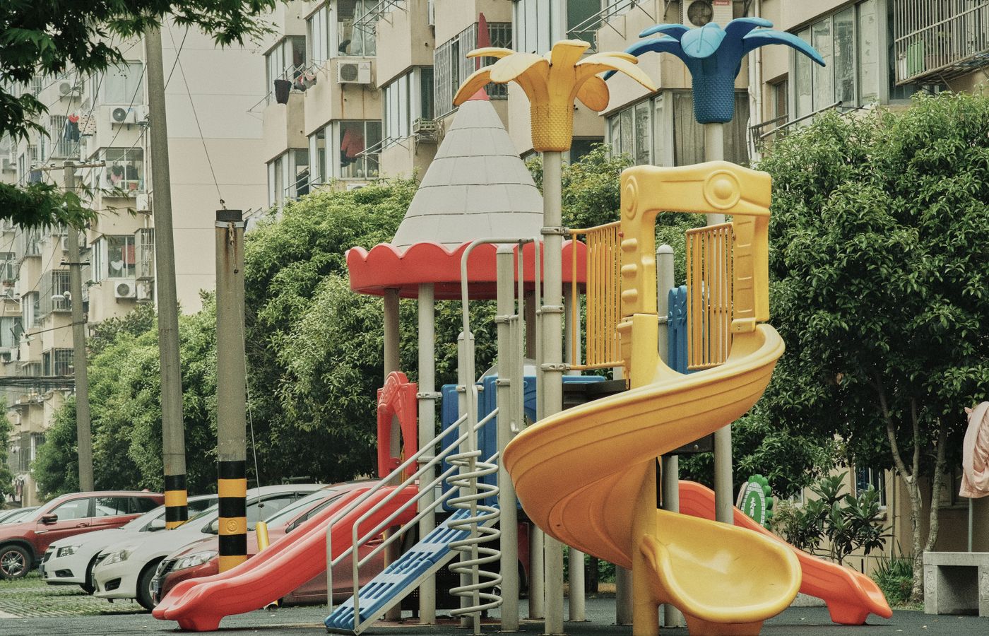 Vibrant playground with slides and equipment in an urban park setting surrounded by apartment buildings.