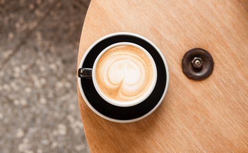 Free A cappuccino with heart latte art in a black cup on a wooden table from above. Stock Photo