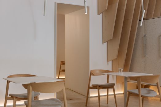 A serene minimalist room with wooden chairs and tables, showcasing modern interior design.
