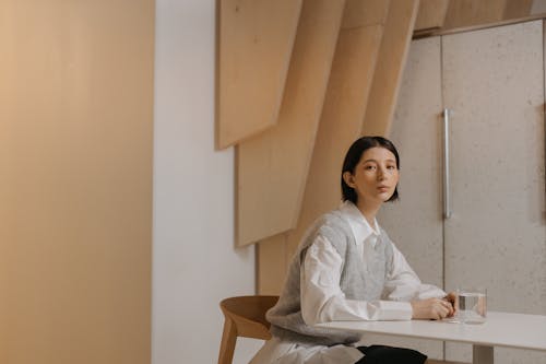 Woman in White Long Sleeve Shirt Sitting on Brown Wooden Chair