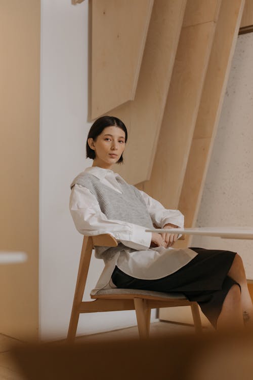 Woman in White Long Sleeve Shirt Sitting Wooden Chair